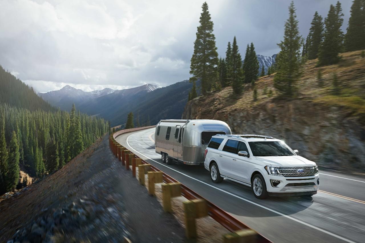 Ford Expedition blanche tirant une caravane sur route montagneuse