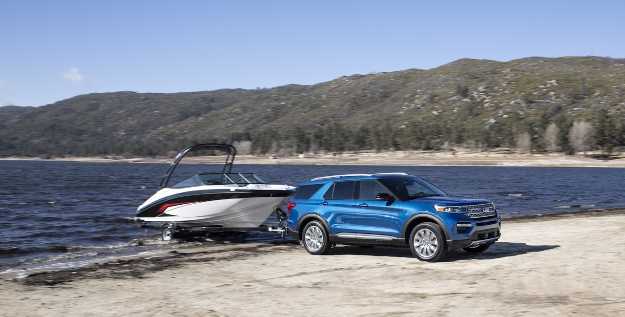 Ford Explorer hybride bleu métallique remorquant un yacht