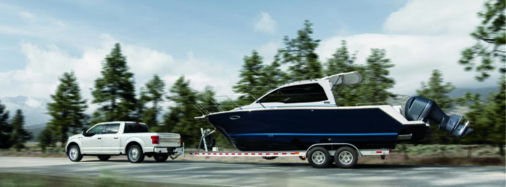Ford F-150 LTD blanc tirant un yacht 2 fois sa grosseur