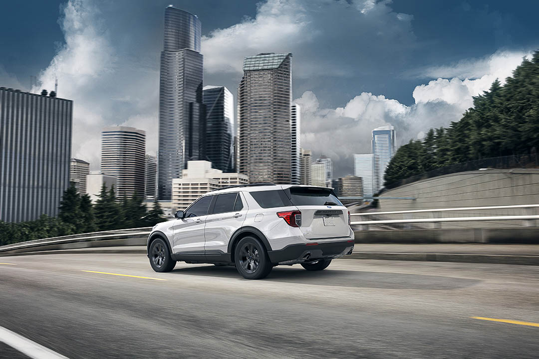 vue trois quart arrière du Ford Explorer 2021 roulant sur une route en ville