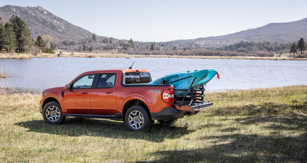 Deux planches de surf installées dans le coffre de conception FlexBed du Maverick Lariat 2022 au bord d'un lac