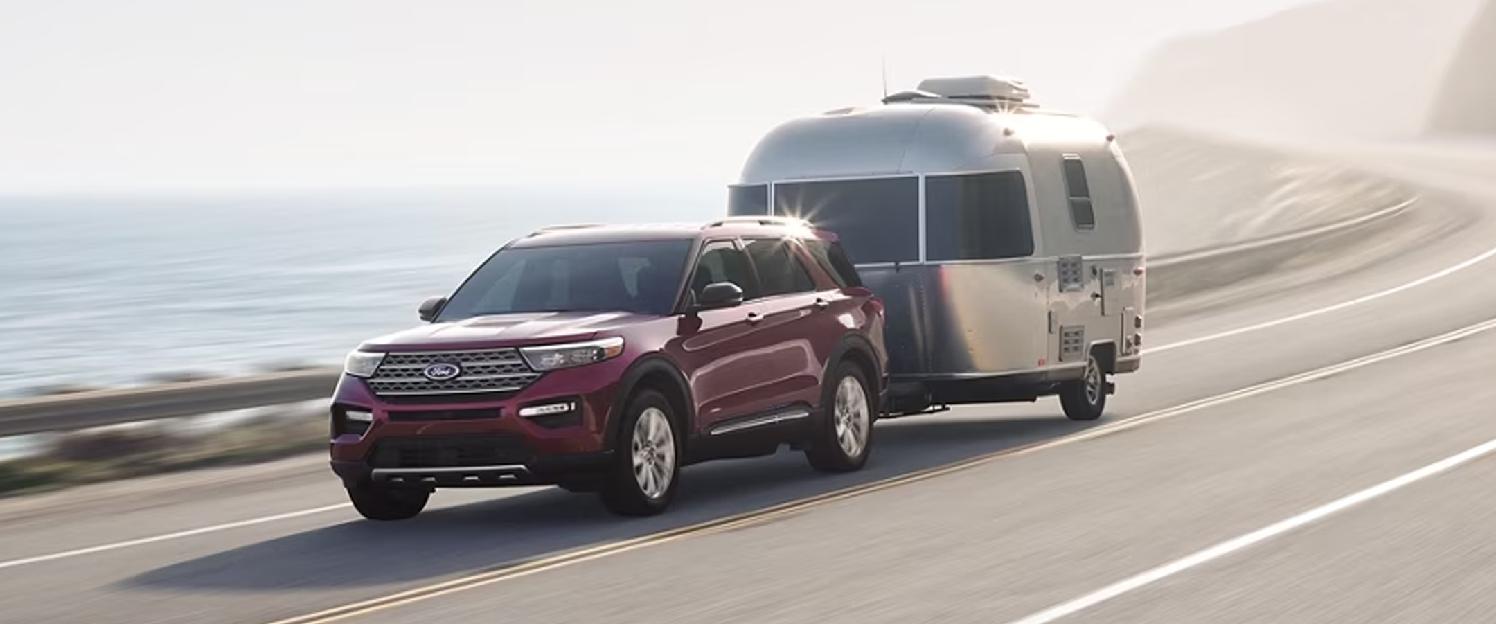 Red 2023 Ford Explorer showcasing its towing abilities around a windy mountain road.