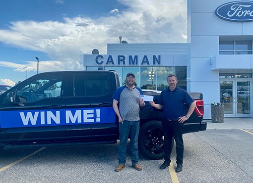 Two men in front of a prize truck at a car dealership