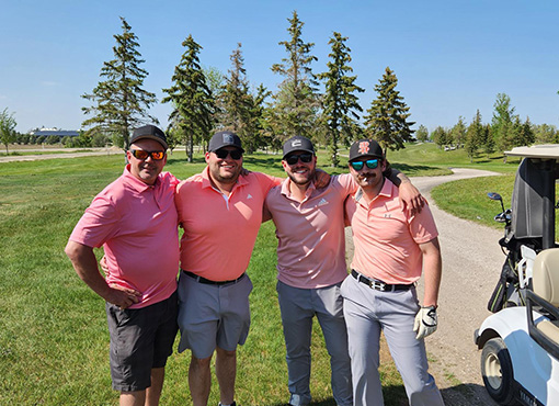 four men standing on a golf course