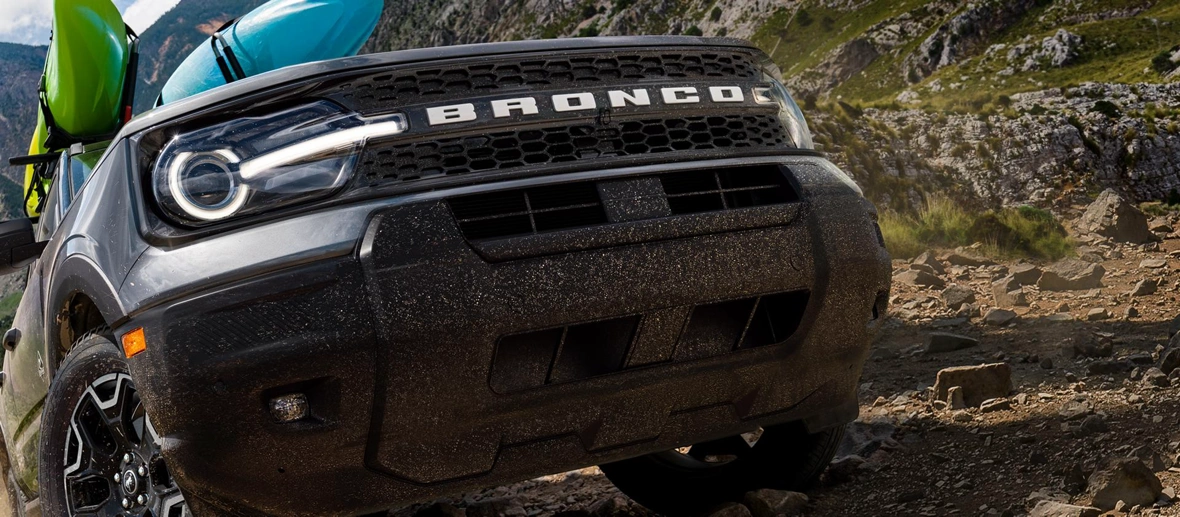 Ford Bronco Sport transportant des kayaks sur un sentier rocheux.