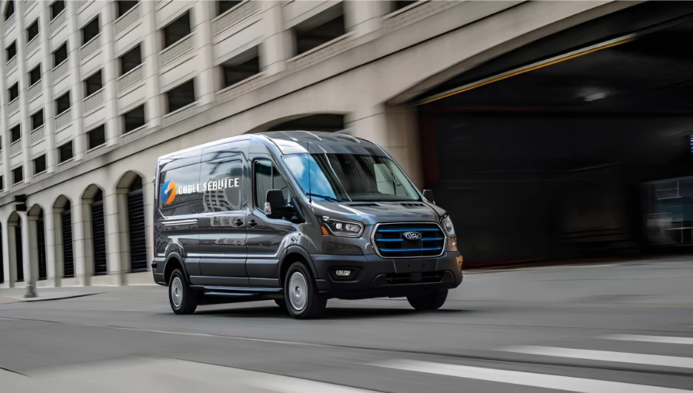 Ford E-Transit électrique gris circulant dans un environnement urbain.