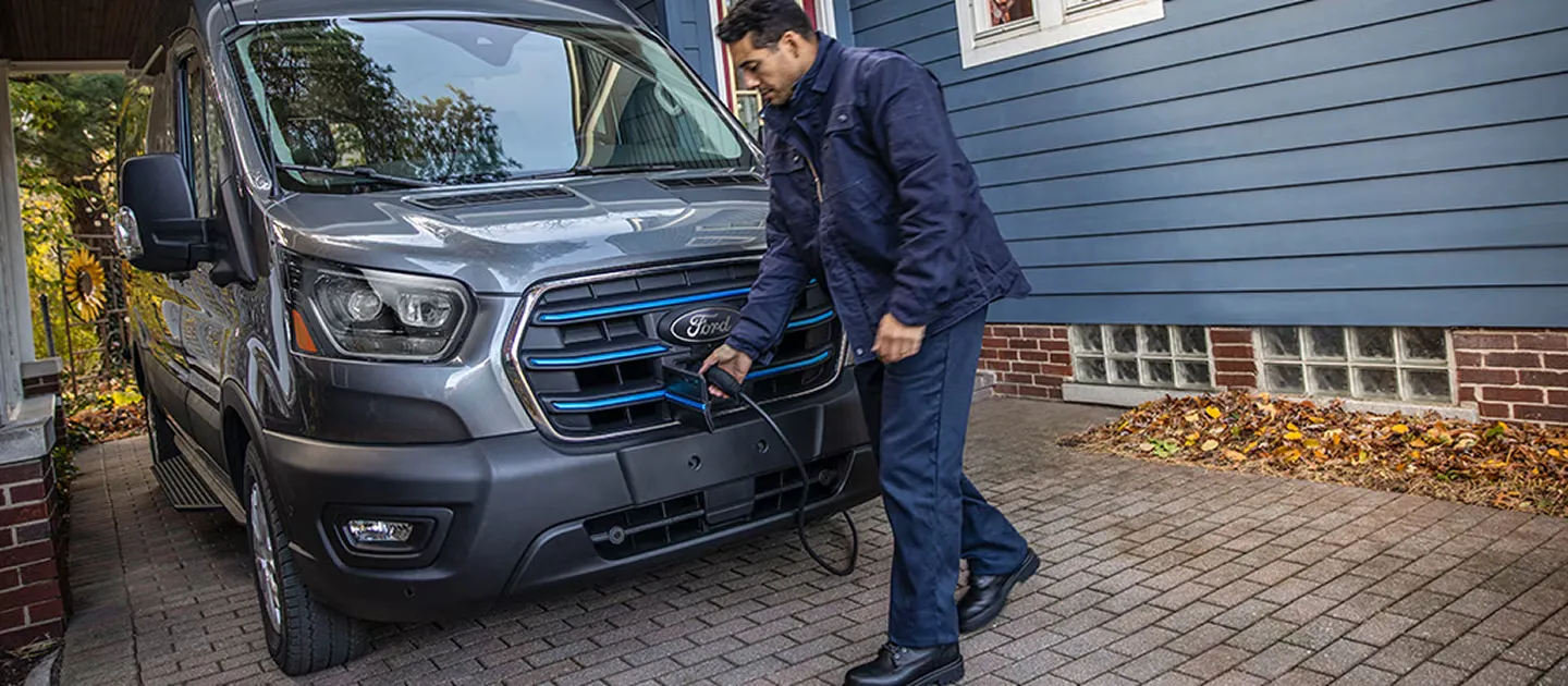 Conducteur branchant un Ford E-Transit électrique à une borne de recharge.