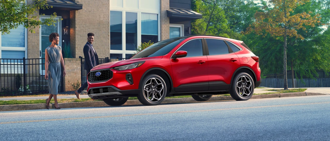Ford Escape hybride rouge stationné dans un quartier résidentiel.