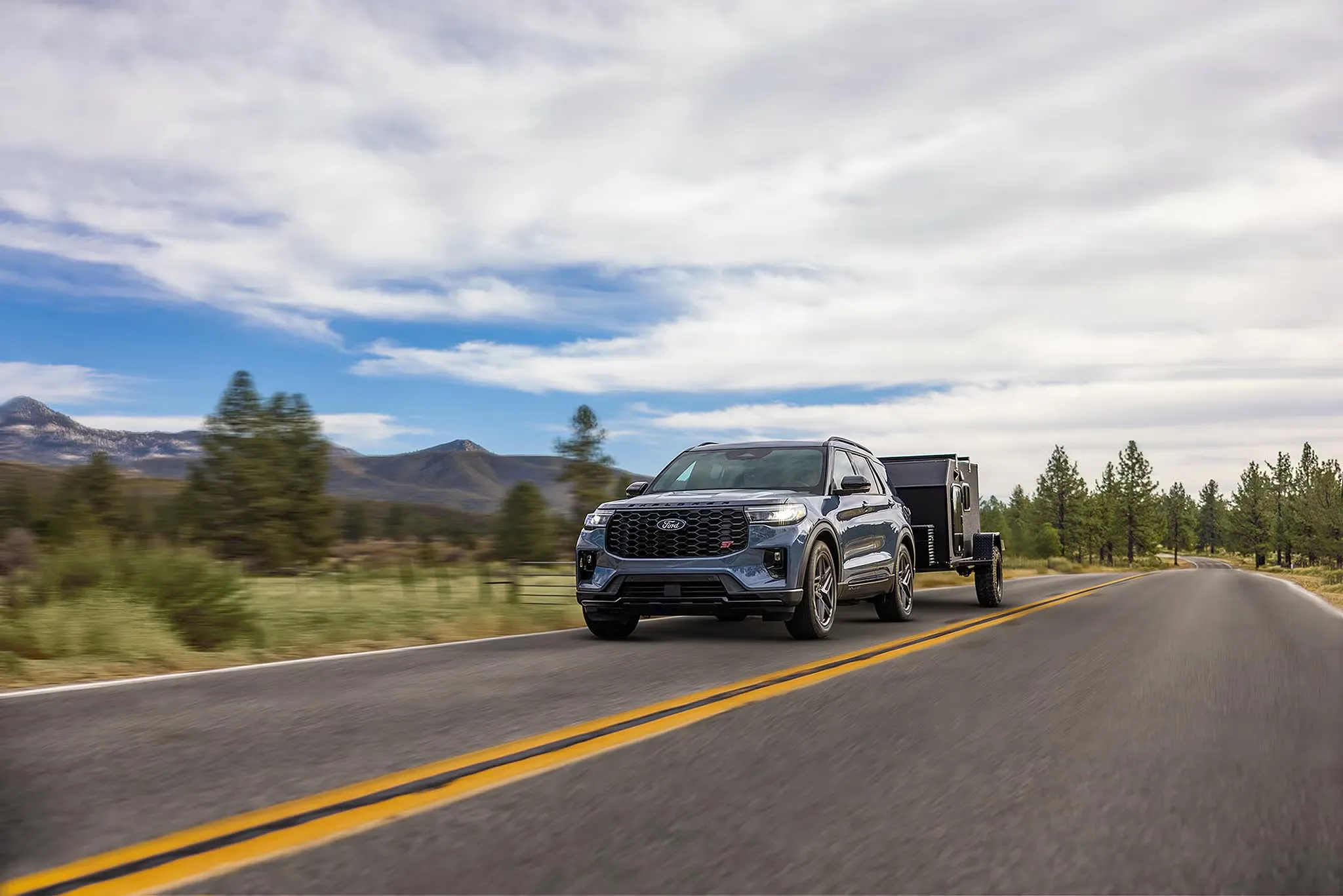 Ford Explorer 2027 remorquant une remorque fermée sur une route de campagne.