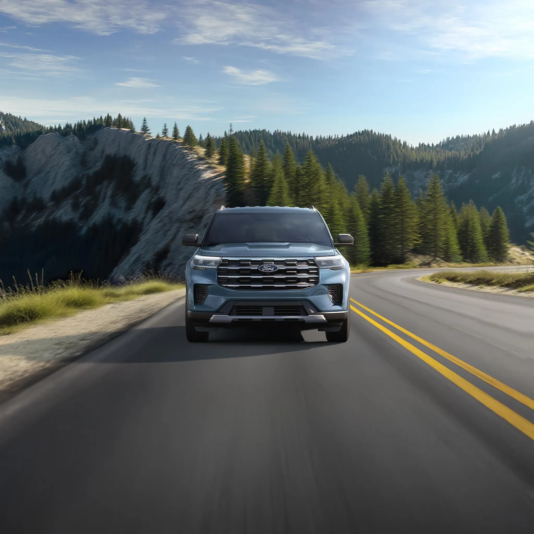 Ford Explorer 2027 vu de face sur une route de montagne bordée de conifères.