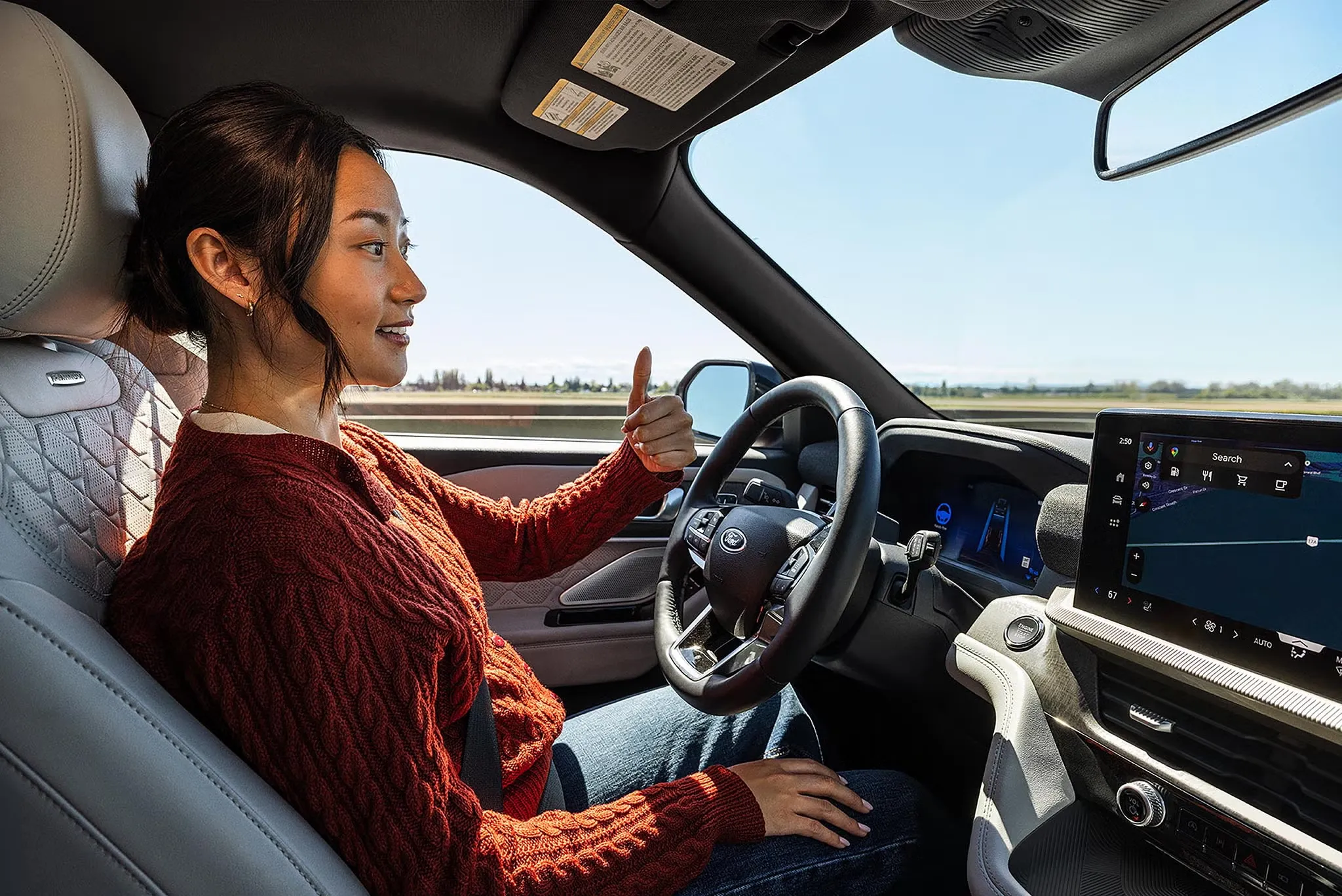 Conductrice au volant du Ford Explorer 2027 avec les mains dégagées du volant, illustrant la conduite mains libres BlueCruise.