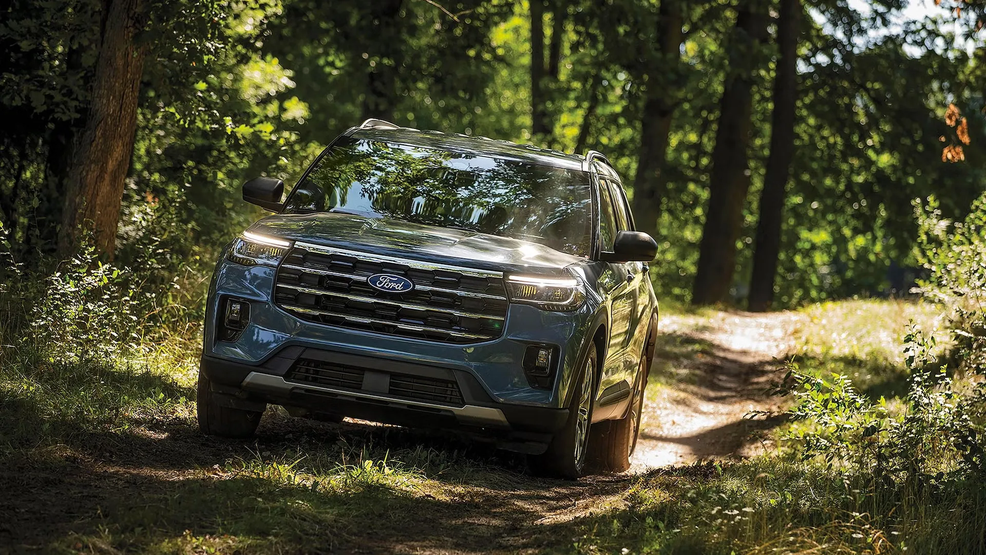 Ford Explorer 2027 vu de trois quarts avant sur un sentier en forêt.