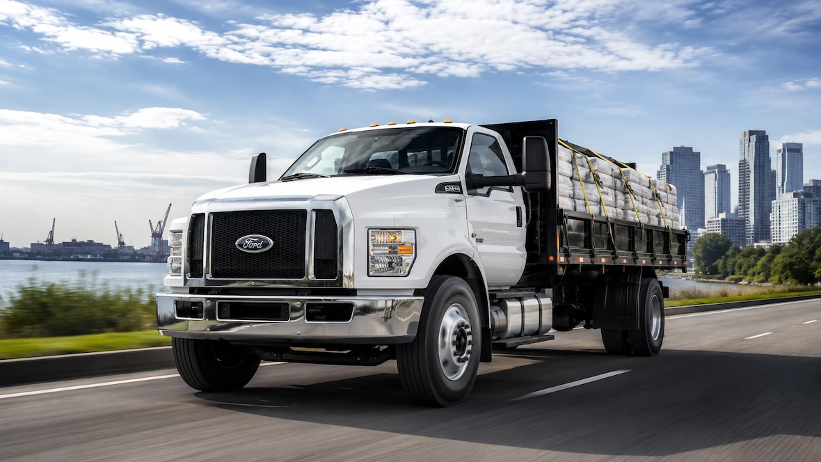 Ford F-650 blanc à plateau transportant une charge sur la route.