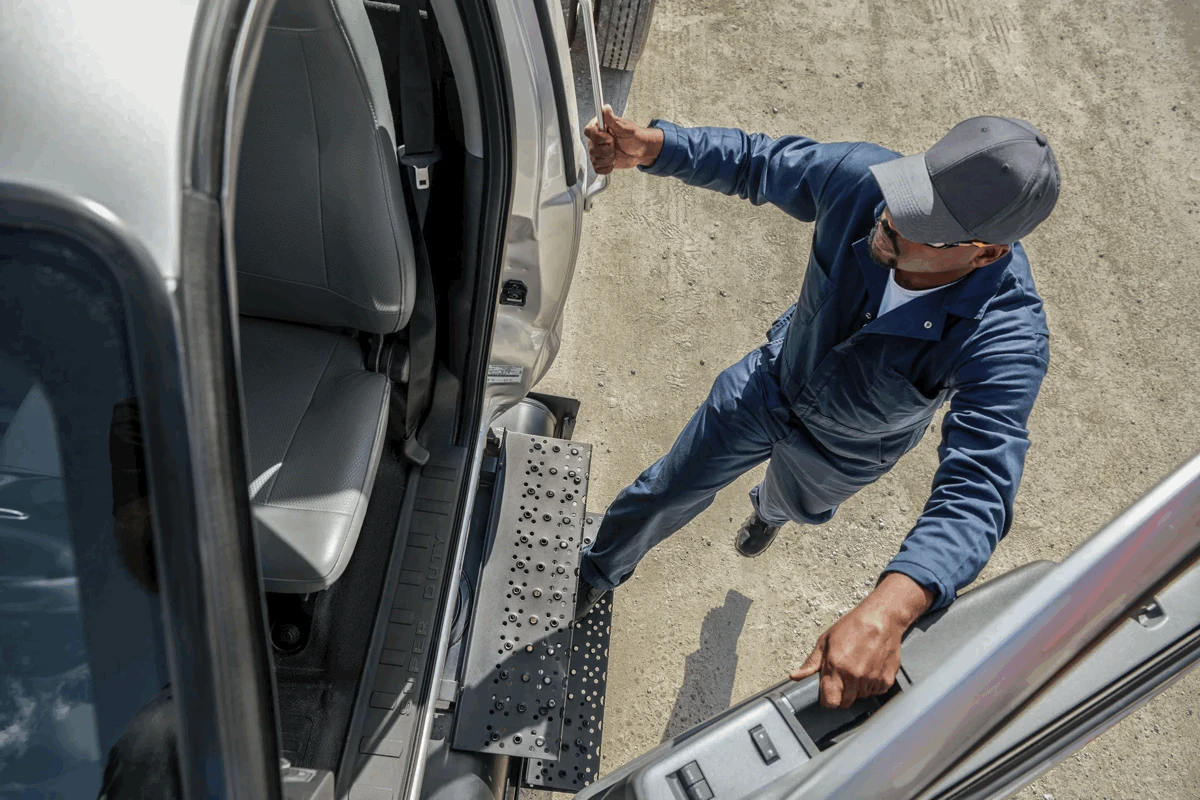 Travailleur montant dans la cabine d’un Ford F-650 à l’aide du marchepied.
