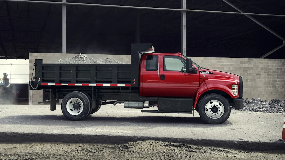 Ford F-650 rouge équipé d’une benne basculante sur un chantier.