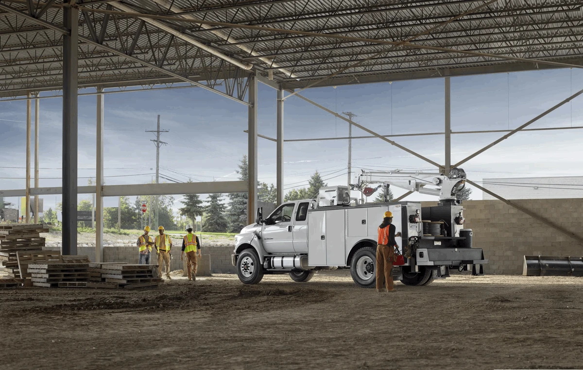 Ford F-750 blanc équipé pour les travaux de service sur un chantier de construction.