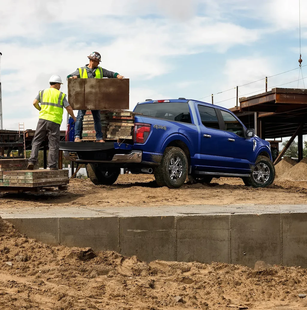 Travailleurs chargeant des matériaux dans un Ford F-150 2026 sur un chantier.