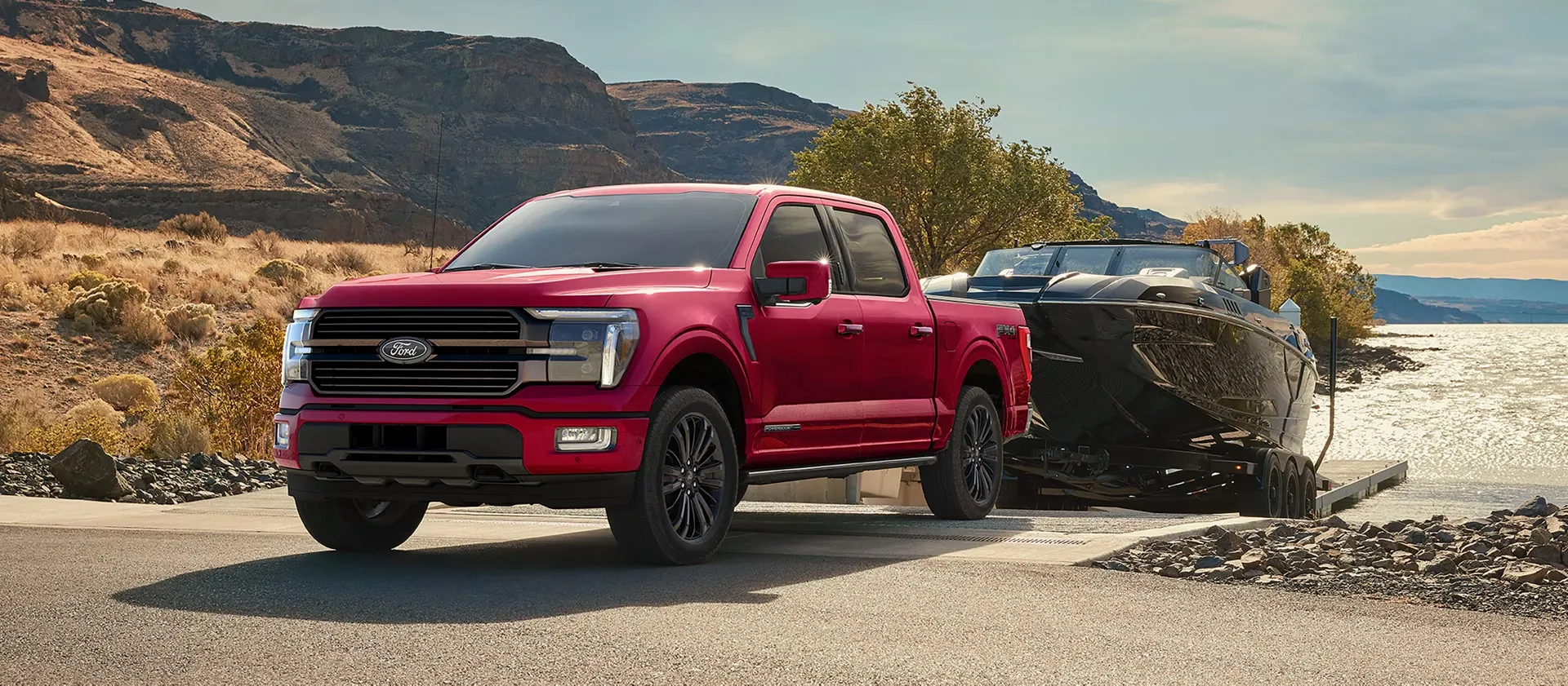 Ford F-150 2026 rouge remorquant un bateau au bord d’un lac.