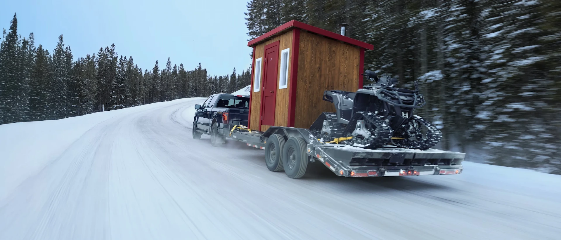 Ford F-150 2026 remorquant une cabane et une motoneige sur une route enneigée.