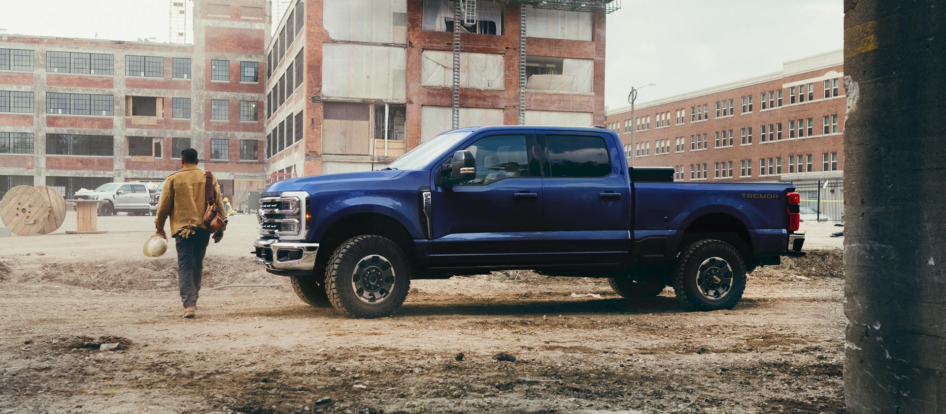 Ford Super Duty F-250 bleu stationné sur un chantier avec un ouvrier.