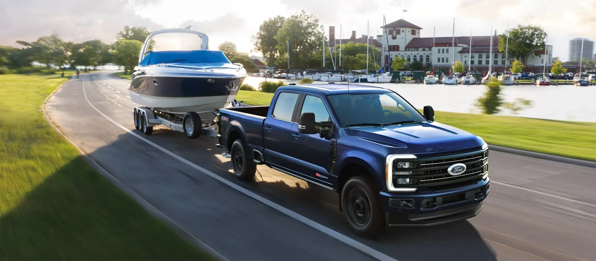 Ford F-250 bleu remorquant un bateau sur une route près d’une marina.