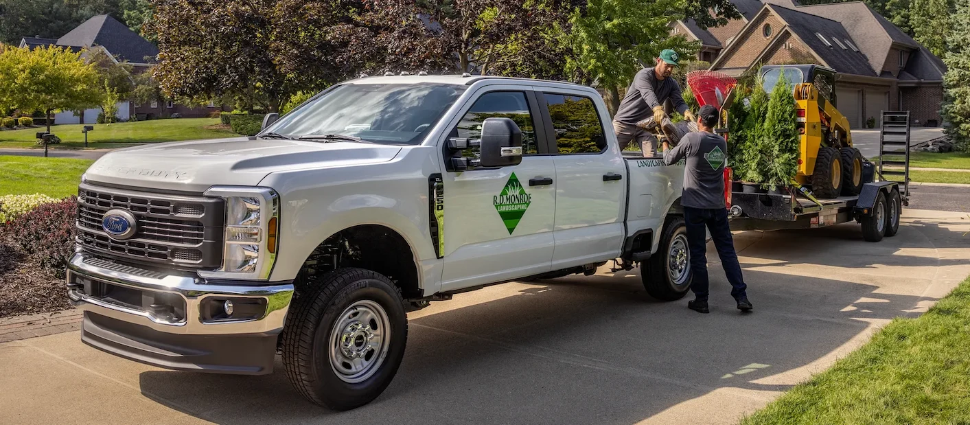 Ford F-250 de travail remorquant une chargeuse sur une remorque.