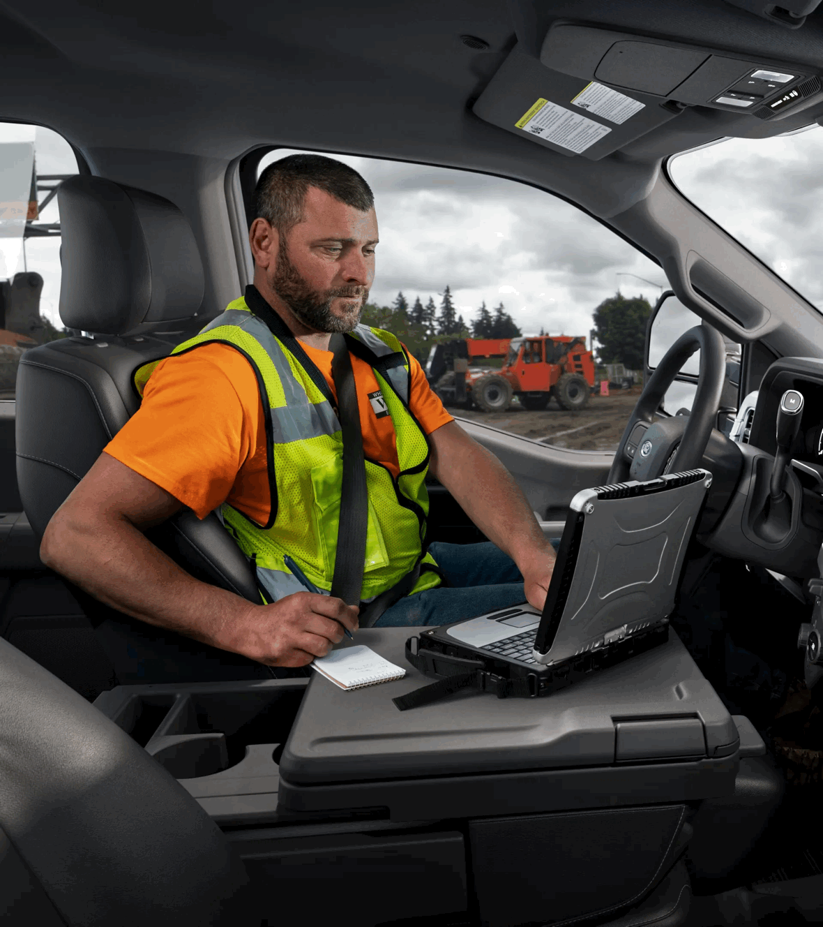 Travailleur consultant un ordinateur dans l’habitacle connecté d’un Ford F-250.