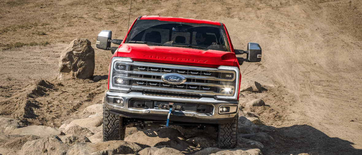 Ford Super Duty F-250 rouge franchissant un parcours rocheux hors route.