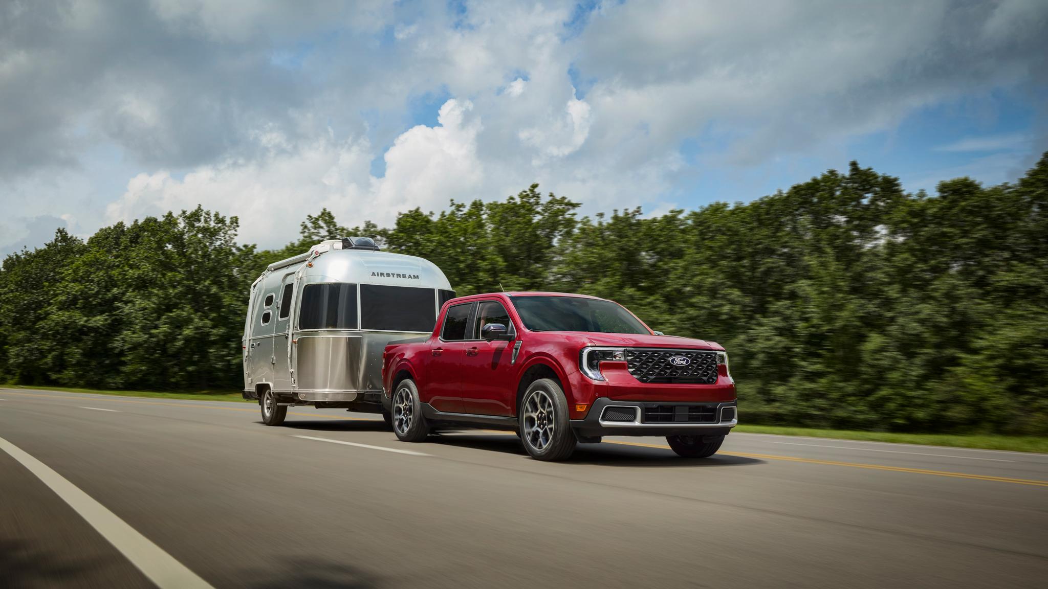 Ford Maverick rouge remorquant une roulotte sur la route.