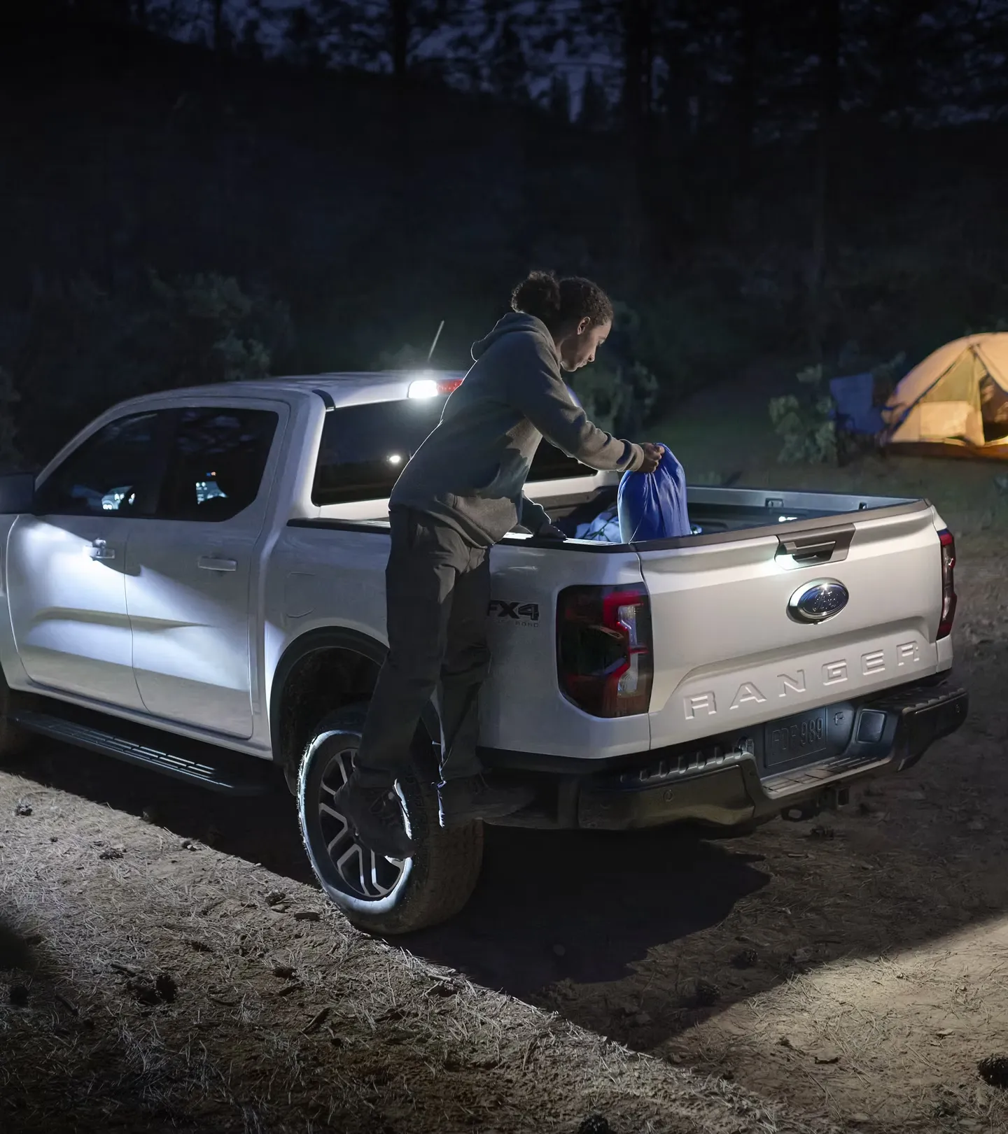 Caisse du Ford Ranger 2026 utilisée pour charger du matériel de camping à la nuit tombée.