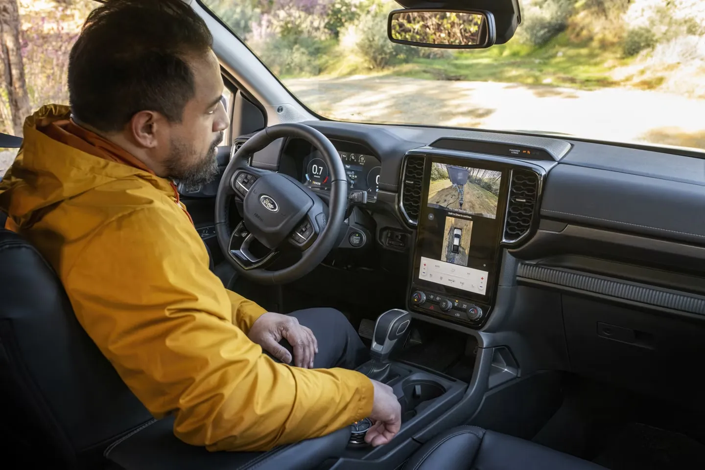 Intérieur du Ford Ranger 2026 avec conducteur, tableau de bord numérique et écran central affichant les caméras.