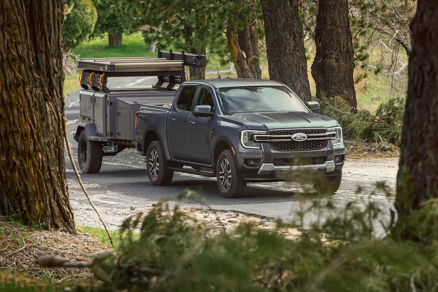 Ford Ranger remorquant une tente-roulotte en forêt.