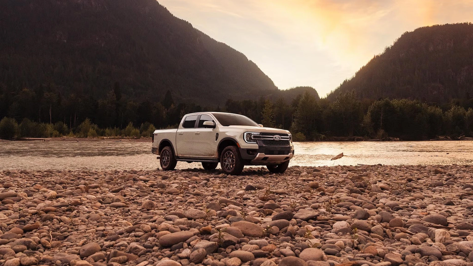 Ford Ranger 2026 blanc stationné sur une rive rocheuse au pied des montagnes.