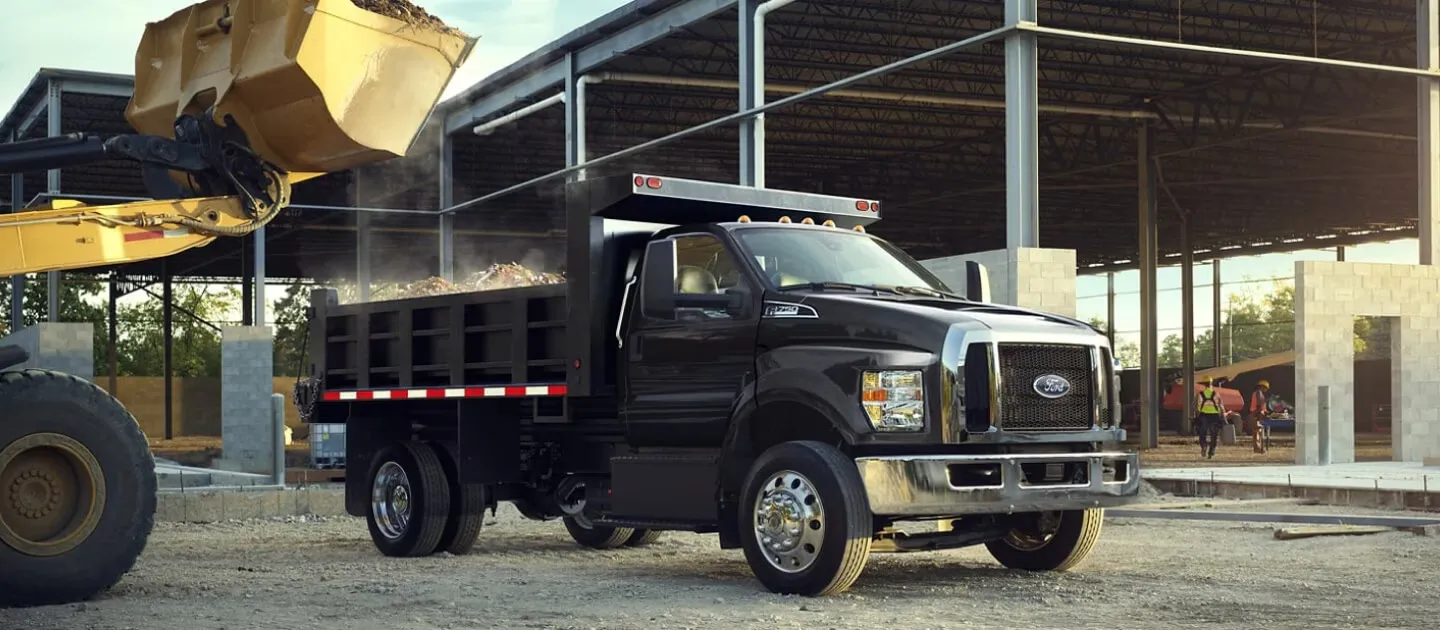 Camion à benne Ford F-750 chargé sur un chantier.